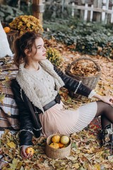 Beautiful girl in autumn garden with yellow flowers and pumpkins