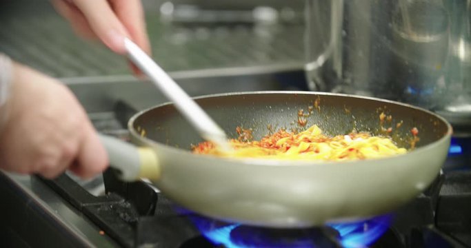 Chef cooking spaghetti pasta food in pan by gas during rural dinner in summer italian resort