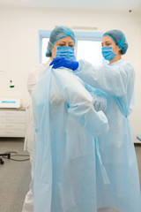 Fototapeta na wymiar a nurse puts a surgeon in a sterile suit before surgery