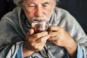 Old people senior man with winter seasonal illness fever cold problems drinking a pharmacy medicine or hot tea to go healthy - concept of mature retired with disease