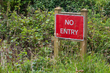 No entry sign in woodland in front of a hedge