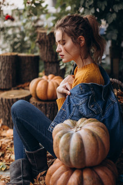 Beautiful girl in autumn garden with yellow pumpkins