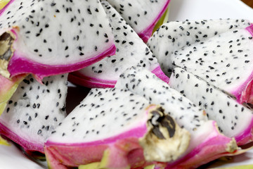 Naklejka premium Healthy dragon fruit or pitaya pieces background, close up of beautiful fresh sliced dragon fruit with texture in the market in thailand. Pitaya is the plant in Cactaceae family or Cactus.