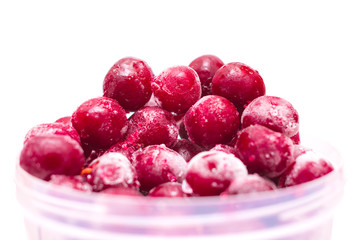 Bunch of winter cherries are isolated on a white background. Frozen cherries are in a plastic bucket. Red fruits is in a round plastic form.