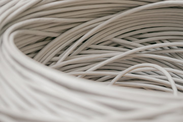 A rolled gray cable is a close up. A bunch of utp wires intertwined with each other. Abstract technological background texture. The concept of wired Internet communications.