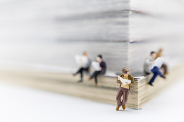 Business, Education and Learning concept. Close up of group of businessman miniature reading with book as background.
