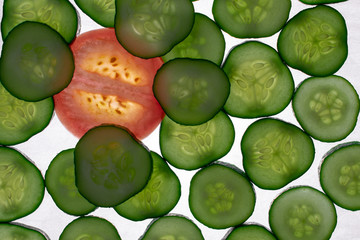 Beautiful, green, red, glowing slices of cucumber and tomato slice, lying on a white background. Cucumber and tomato slices, translucent flash.