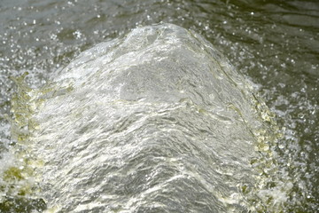 a strong stream of water from the pipe flows into the river, air bubbles in the water, filling the...