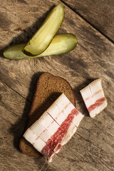 Bacon, bread and cucumber over wooden background. Russian and ukrainian traditional appetizer