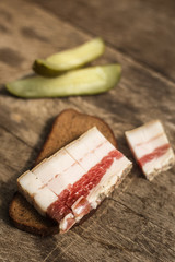 Bacon, bread and cucumber over wooden background. Russian and ukrainian traditional appetizer