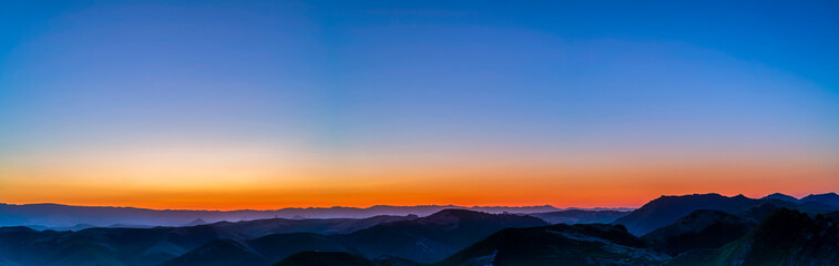 Fototapeta na wymiar Panorama of Sunrise over Silhouetted Mountains