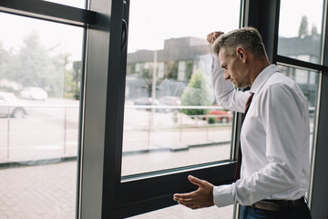 Fototapeta premium upset businessman standing with clenched fist near windows