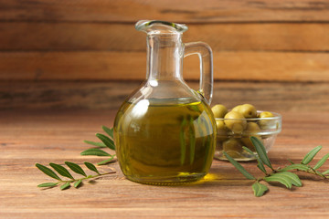 olive oil, green leaves and olives on the table.