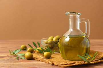 olive oil, green leaves and olives on the table.