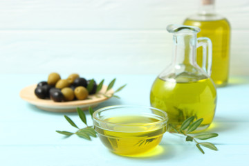 olive oil, green leaves and olives on the table.