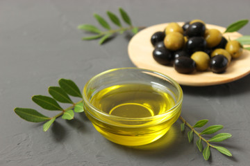 olive oil, green leaves and olives on the table.