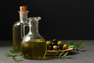 olive oil, green leaves and olives on the table.