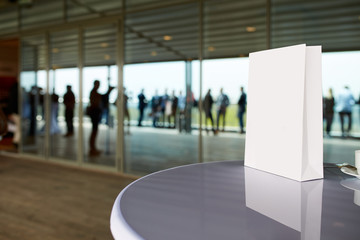 Blank paper bag on the table at business meeting with blurry people on background