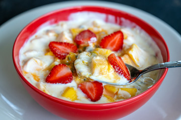 Mango, passion fruit, strawberry and yogurt brulee. Fruit dessert on breakfast with wedges of perfectly ripe in season mangoes and strawberry, covered fresh passion fruit pulp
