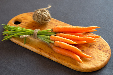 Small carrots on a cutting natural wood board, top view