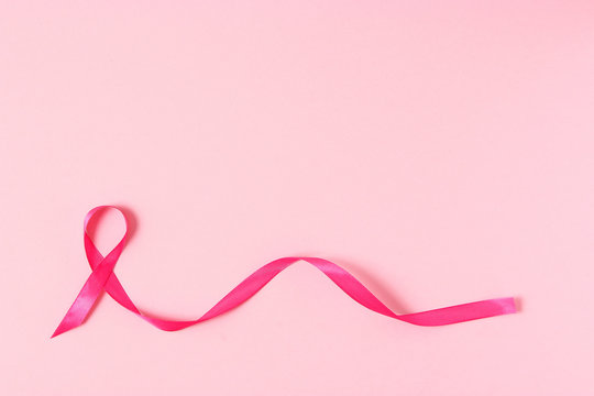 Pink ribbon on a colored background top view. Cancer disease.