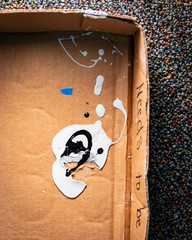 Spilled paint drops in cardboard box