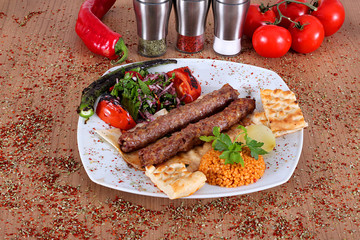 Roasted turkey kebabs with fresh pepper and vegetables on a wooden table filled with Turkish spices
