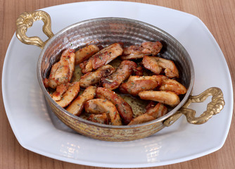 Serving fried chicken in copper dish and white plate from close angle on wooden table