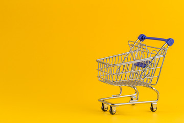 Shopping cart on bright yellow paper background
