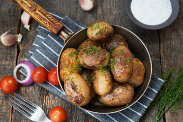 Fried potatoes with herbs and sour cream in a rustic style on a wooden table