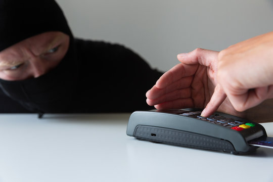 Thief is stealing pin code and identity on payment (pos) terminal machine. Crime concept