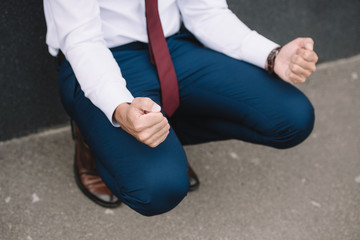 cropped view of businessman sitting with clenched fists