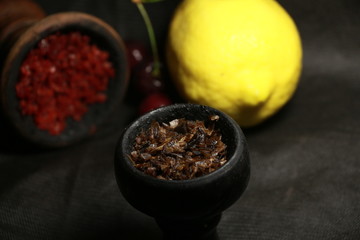 bowl with tobacco for hookah. fruits on a black background