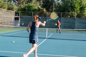 Men and women taking an outdoor tennis lesson