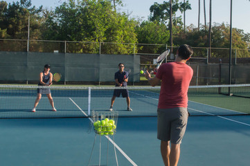 Men and women taking an outdoor tennis lesson