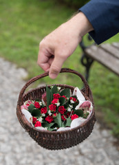 Hand hält Korb mit Blumenanstecker bei einer Hochzeit 