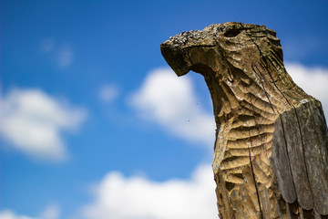 symbolic wooden eagle on a background of blue sky with white clouds