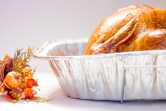 Side Angle of Roasted Turkey in a Foil Roasting Pan on a White Background