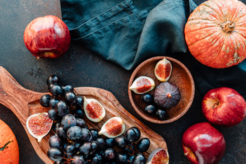 Top view of Autumn food still life with season fruits and vegetables like Bangalore blue grape, red apples, pumpkins and figs on a table.