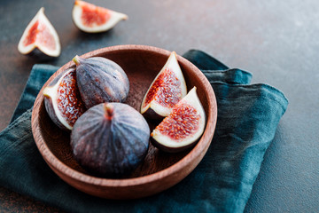 Macro photo of ripe quartes figs in a wooden small bowl on a table.