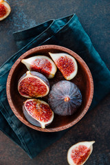 Top view of ripe quartes figs in a wooden small bowl on a table.