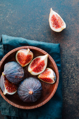 Top view of ripe quartes figs in a wooden small bowl on a table.