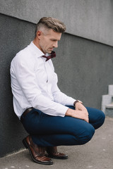 upset businessman in formal wear sitting outside