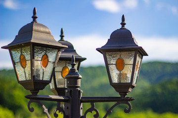 old-style street lamps on a background of green hills and blue sky