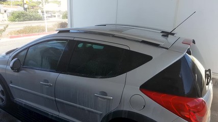 A man in a car wash, washes a dirty car.