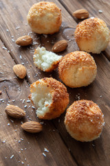 Coconut cookies with almonds lie on a wooden table.