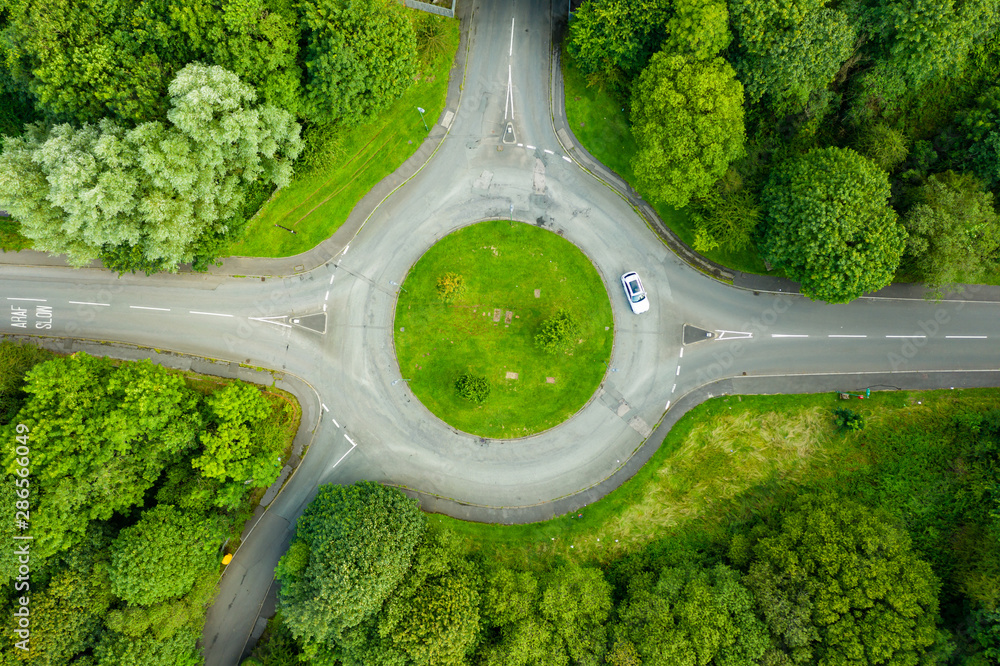 Wall mural top down aerial drone view of a small traffic roundabout on a quiet road - Wall murals