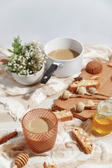 Coffee with milk, cookies, cinnamon and fruits on the tablecloth.