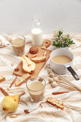 Coffee with milk, cookies, cinnamon and fruits on the tablecloth.