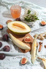 Cut appetizing ripe melon and drinks in stained-glass glasses on a table with a blue tablecloth.